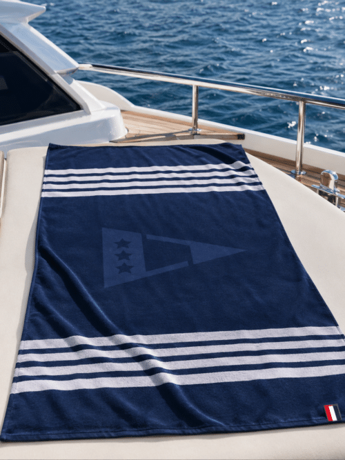 Telo mare in microfibra Scuola Nautica Italiana colore blu disteso su yacht dettaglio nautico